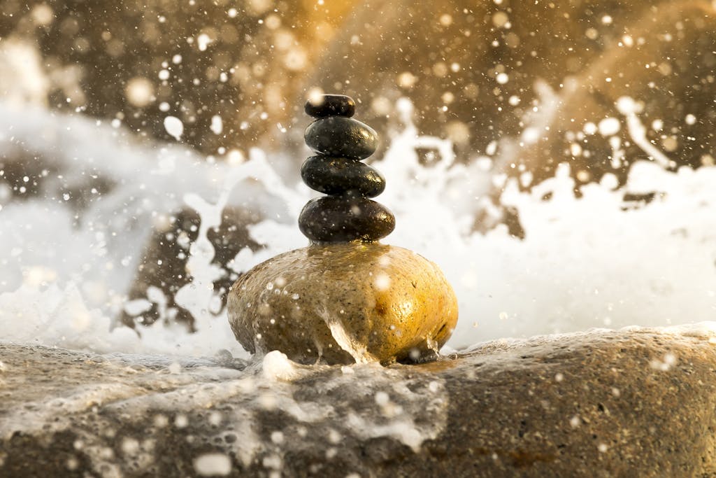 Peaceful balance of stacked stones amidst splashing water, creating a zen-like ambiance.