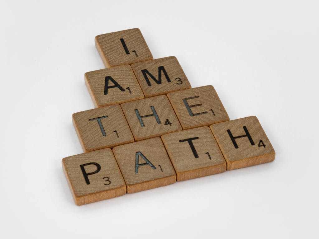 Scrabble tiles arranged to form the quote 'I am the path' on a white surface.
