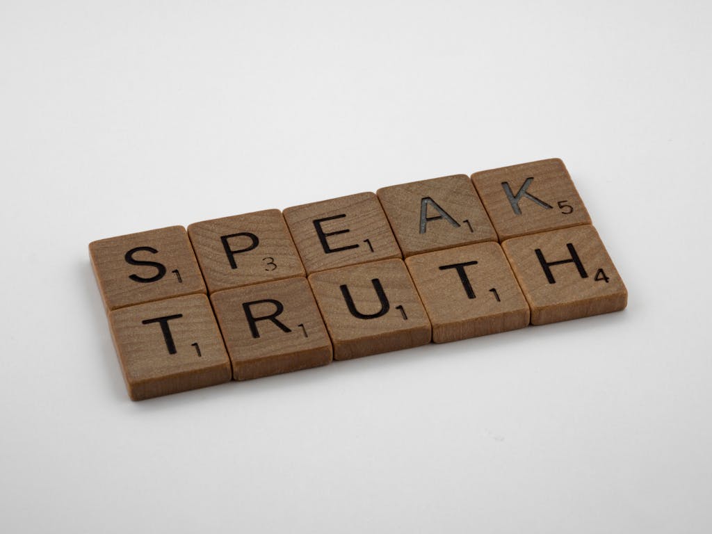 Wooden Scrabble tiles forming the words 'Speak Truth' on a white background.