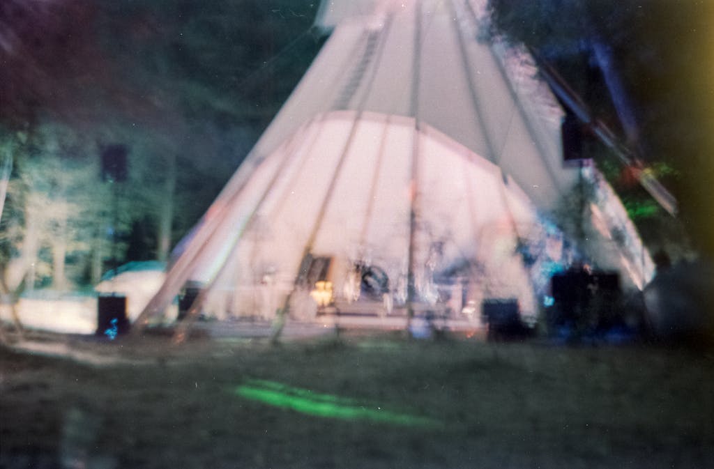 An artistic view of a glowing tent in a forest at night with blurred focus.